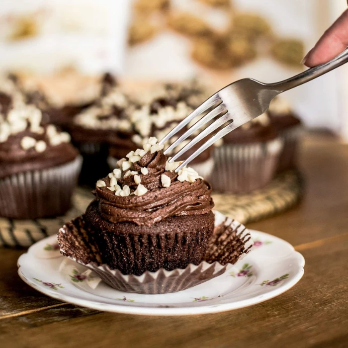 Chocolate cupcake on a plate with a fork and a softly blurred background.